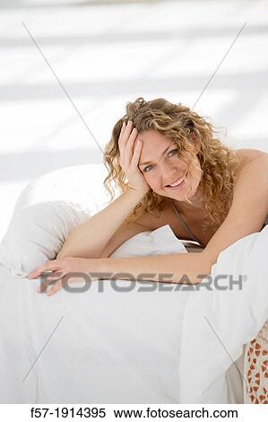 Stock Photography - Attractive young woman waking up in her bed. Fotosearch