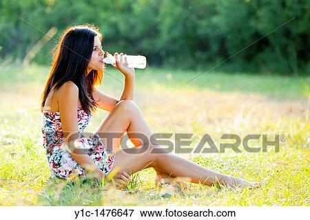 Attractive young woman with a bottle of water on the grass View Large Photo Image Stock Photo - Attractive young woman with a bottle of water on the grass. Fotosearch