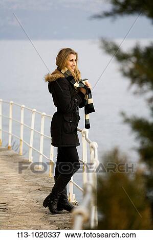 Stock Photo - Attractive young woman with a scarf is looking at the sea. Fotosearch