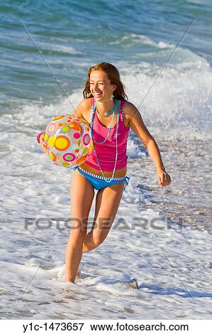 Stock Photo - Attractive young woman with an inflatable ball on the beach. Fotosearch