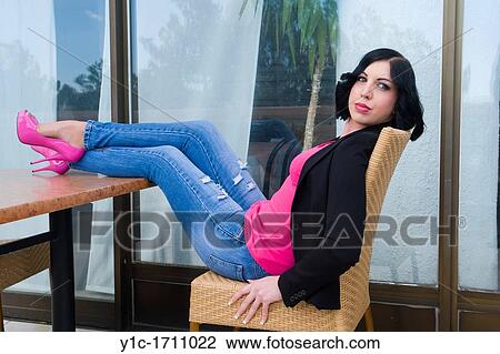 Stock Image - Attractive young woman with legs on a table. Fotosearch