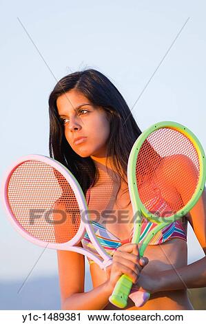 Stock Image - Attractive young woman with two colorful tennis rackets in hands. Fotosearch