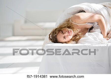 Attractive young woman wrapped in her quilt in bed View Large Photo Image Stock Image - Attractive young woman wrapped in her quilt in bed. Fotosearch