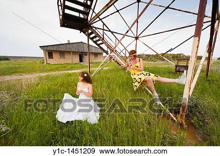 Stock Photo - Attractive young women on the grass next to a derelict metal frame construction. Fotosearch