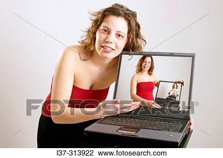 Auburn-haired girl showing a laptop computer which has in it another image of the same girl View Large Photo Image Stock Image - Auburn-haired girl showing a laptop computer which has in it another image of the same girl. Fotosearch
