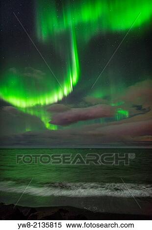 Stock Photography - Aurora Borealis or Northern lights over waves breakiing on the beach in Seltjarnarnes, Reykjavik, Iceland.. Fotosearch