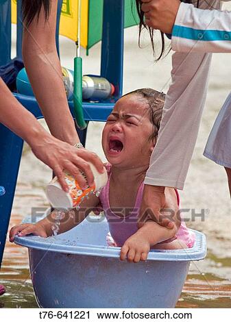 Baby cries while getting a curbside bath during the Lao Songkran New Year, Luang Prabang View Large Photo Image Stock Image - Baby cries while getting a curbside bath during the Lao Songkran New Year, Luang Prabang. Fotosearch