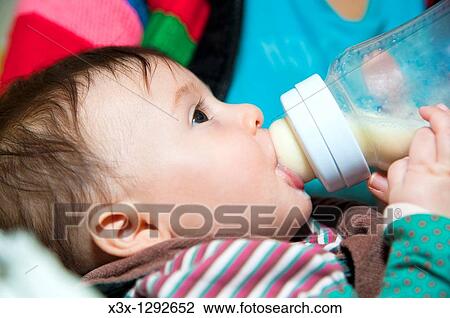 Stock Image - Baby girl bottle feeding. Fotosearch