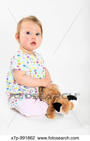Stock Image - Baby Girl on sitting white backdrop with stuffed animal. Fotosearch