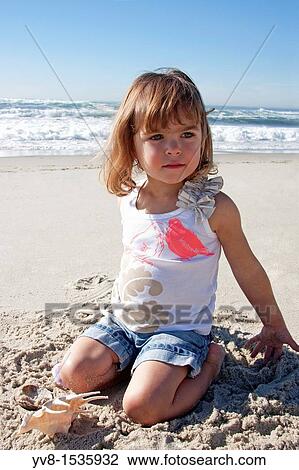 Stock Image - Baby girl playing at the beach. Fotosearch