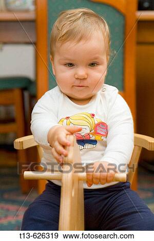 Baby girl playing on wooden horse toy View Large Photo Image Stock Photo - Baby girl playing on wooden horse toy. Fotosearch