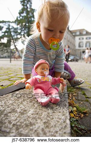 Baby girl playing with doll in the streets of Z? rich, Switzerland. View Large Photo Image Stock Photograph - Baby girl playing with doll in the streets of Z? rich, Switzerland.. Fotosearch