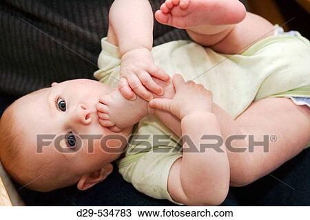 Baby girl putting toes in her mouth View Large Photo Image Stock Image - Baby girl putting toes in her mouth. Fotosearch