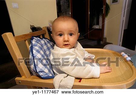 Baby girl sitting on a wooden highchair waiting to be fed. View Large Photo Image Stock Photo - Baby girl sitting on a wooden highchair waiting to be fed.. Fotosearch