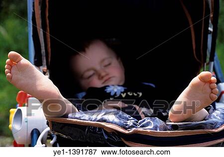 Stock Photo - Baby girl sleeping in her stroller, France. Fotosearch