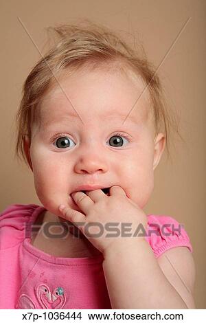 Picture - Baby girl with fingers in her mouth. Fotosearch