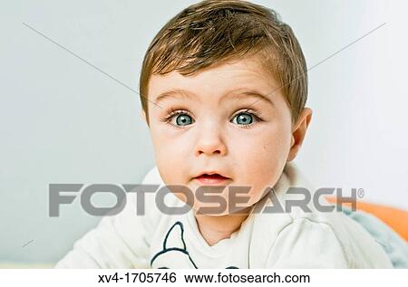 Stock Photograph - Baby look at camera posed at bedroom. Fotosearch