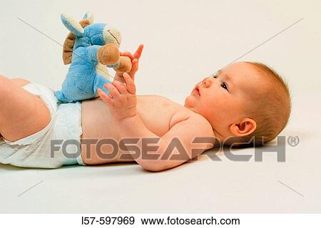Baby lying on back, playing with toy, playing with soft touch plush animal, studio, Oetwil am See, Zuerich, Switzerland View Large Photo Image Stock Photo - Baby lying on back, playing with toy, playing with soft touch plush animal, studio, Oetwil am See, Zuerich, Switzerland. Fotosearch