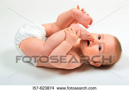 Baby lying on back, wearing nappies, playing with its feet, Studio, Oetwil am See, Zuerich, Switzerland View Large Photo Image Picture - Baby lying on back, wearing nappies, playing with its feet, Studio, Oetwil am See, Zuerich, Switzerland. Fotosearch