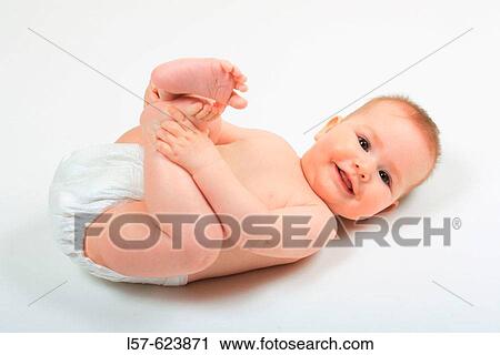Baby lying on back, wearing nappies, playing with its feet, Studio, Oetwil am See, Zuerich, Switzerland View Large Photo Image Stock Image - Baby lying on back, wearing nappies, playing with its feet, Studio, Oetwil am See, Zuerich, Switzerland. Fotosearch
