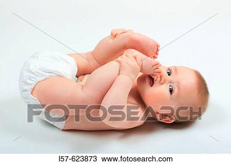 Baby lying on back, wearing nappies, playing with its feet, Studio, Oetwil am See, Zuerich, Switzerland View Large Photo Image Stock Image - Baby lying on back, wearing nappies, playing with its feet, Studio, Oetwil am See, Zuerich, Switzerland. Fotosearch