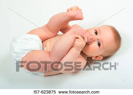 Baby lying on back, wearing nappies, playing with its feet, Studio, Oetwil am See, Zuerich, Switzerland View Large Photo Image Stock Photography - Baby lying on back, wearing nappies, playing with its feet, Studio, Oetwil am See, Zuerich, Switzerland. Fotosearch