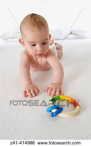 Baby reaching for a toy View Large Photo Image Stock Photograph - Baby reaching for a toy. Fotosearch