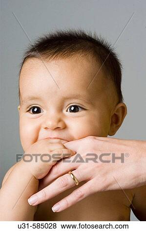 Stock Photo - Baby scratching his gums with his mother's hand.. Fotosearch