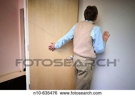 Stock Photograph - Back of a man standing by a door in an office building lobby. Fotosearch