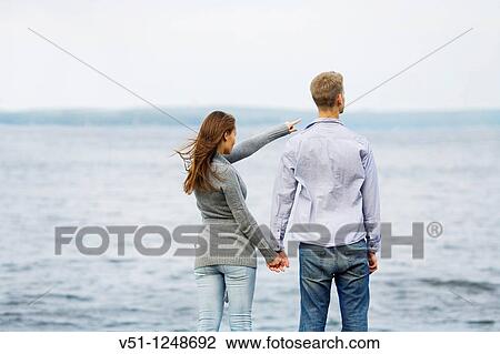 Back view of a couple by the sea pointing View Large Photo Image Stock Image - Back view of a couple by the sea pointing. Fotosearch