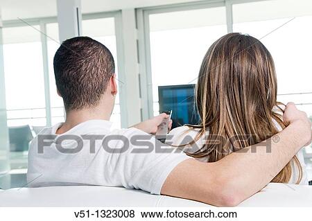 Back view of a couple watching TV at home View Large Photo Image Stock Photo - Back view of a couple watching TV at home. Fotosearch