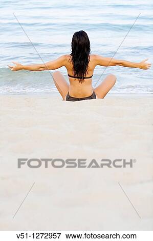 Stock Photo - Back view of a young woman stretching at the beach. Fotosearch
