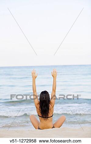 Back view of a young woman stretching at the beach View Large Photo Image Stock Photo - Back view of a young woman stretching at the beach. Fotosearch