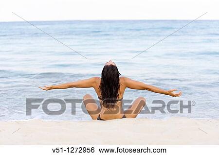 Back view of a young woman stretching at the beach View Large Photo Image Stock Photograph - Back view of a young woman stretching at the beach. Fotosearch