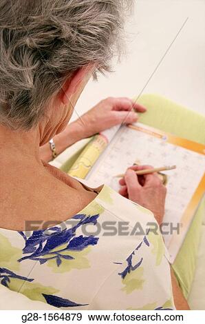 Back view of Senior woman exercising her memory by doing crosswords to avoid Alzheimer problems View Large Photo Image Stock Photo - Back view of Senior woman exercising her memory by doing crosswords to avoid Alzheimer problems. Fotosearch