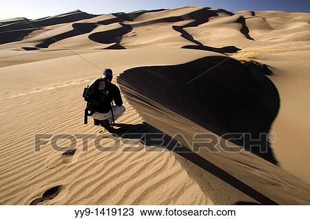 Stock Image - Backpacker on dunes - Great Sand Dunes National Park and Preserve - near Mosca, Colorado. Fotosearch
