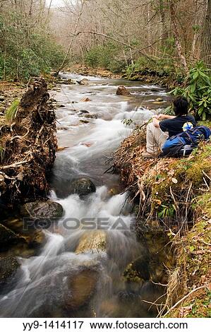 Stock Photo - Backpacker resting by the Davidson River - Pisgah National Forest - near Brevard, North Carolina, USA. Fotosearch