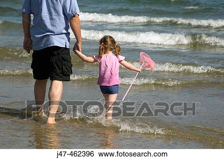 Backshot of a 3 year old girl standing with her dad in the sea with a net. View Large Photo Image Stock Photograph - Backshot of a 3 year old girl standing with her dad in the sea with a net.. Fotosearch