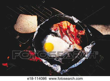 Bacon and eggs, breakfast cooked over campsite fire pit. View Large Photo Image Stock Photograph - Bacon and eggs, breakfast cooked over campsite fire pit.. Fotosearch