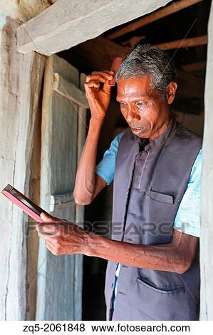 Stock Photo - Baiga man lookin in mirror. Baiga Tribe, Chada village, Madhya Pradesh, India.. Fotosearch