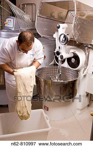 Stock Photo - baker who prepares the mixer with the dough for the bread to put in the oven. Fotosearch
