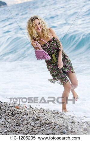 Stock Photography - Balancing on one foot young woman on the beach. Fotosearch