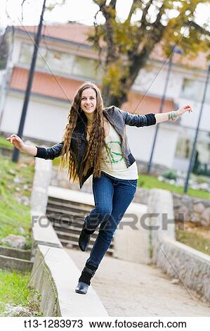 Stock Image - Balancing on one leg in the park young woman. Fotosearch