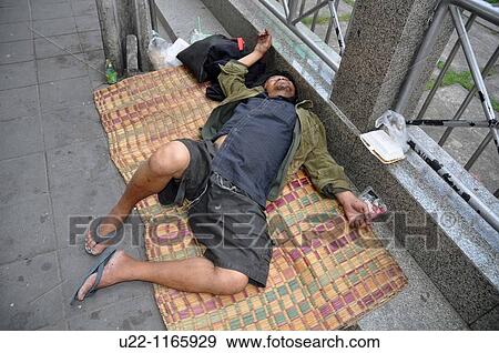 Stock Photo - Bangkok (Thailand): a man sleeping on the sidewalk, daytime. Fotosearch