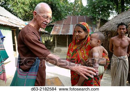BANGLADESH. American Catholic missionary priest in Narail. Visiting a sick child who he will refer for medical treatment. View Large Photo Image Picture - BANGLADESH. American Catholic missionary priest in Narail. Visiting a sick child who he will refer for medical treatment.. Fotosearch