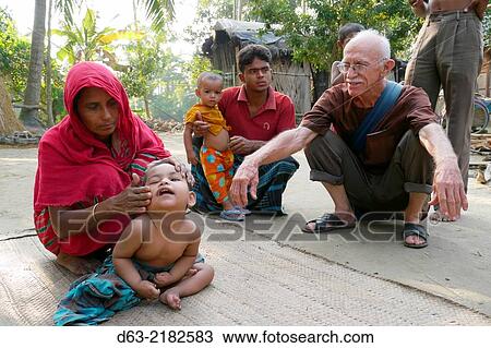 Stock Image - BANGLADESH. American Catholic missionary priest in Narail. Visiting a sick child who he will refer for medical treatment.. Fotosearch
