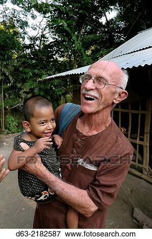 BANGLADESH. American Catholic missionary priest in Narail. Visiting a sick child who he will refer for medical treatment. View Large Photo Image Stock Photo - BANGLADESH. American Catholic missionary priest in Narail. Visiting a sick child who he will refer for medical treatment.. Fotosearch