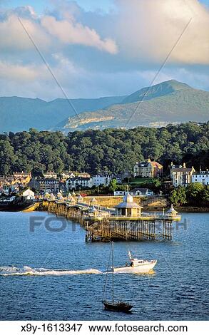 Bangor Pier and town, Gwynedd, north Wales, UK Looking across the Menai Strait from Anglesey to the mountains of Snowdonia View Large Photo Image Stock Photo - Bangor Pier and town, Gwynedd, north Wales, UK Looking across the Menai Strait from Anglesey to the mountains of Snowdonia. Fotosearch