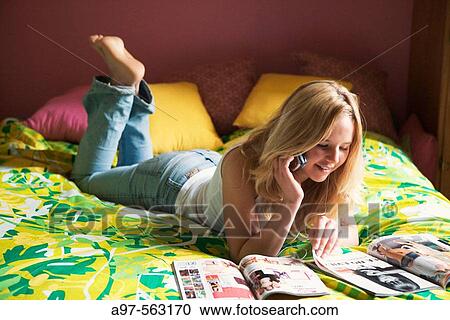 Barefoot blonde teen girl laying on bed reading magazines, talking on cellphone, and listening to i-pod. View Large Photo Image Stock Image - Barefoot blonde teen girl laying on bed reading magazines, talking on cellphone, and listening to i-pod.. Fotosearch