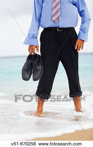 Stock Photo - Barefoot businessman standing by the sea. Fotosearch